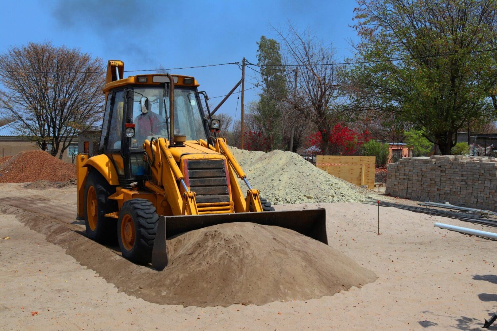 A yellow tractor is in the dirt and has a bucket.